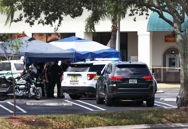  Pegawai syerif Palm Beach County berdiri di luar kedai runcit Publix di Florida di mana seorang wanita, seorang lelaki dan seorang kanak-kanak ditemui mati kelmarin. — Gambar AFP