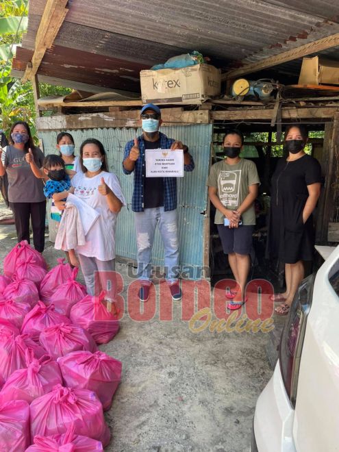  Ijok (tengah) semasa mengagihkan bantuan bakul makanan sumbangan KJRI KK di Sandakan.