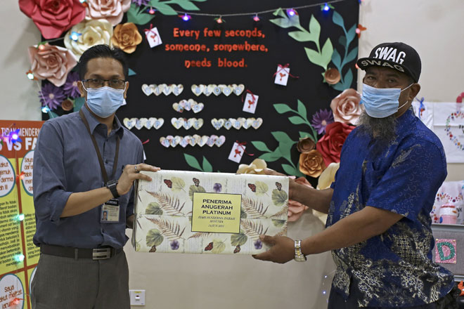 Dr Firdaus Che Ros (kiri) menyampaikan cenderahati kepada penderma darah tertinggi Nor Aziman iaitu sebanyak 100 kali menderma darah ketika ditemui Bernama sempena Hari Derma Darah Sedunia di Pusat Derma Darah di Seremban, semalam. — Gambar Bernama