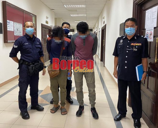 Tertuduh (dua kiri) diiringi polis semasa berada di lobi Mahkamah Kuching, hari ini.