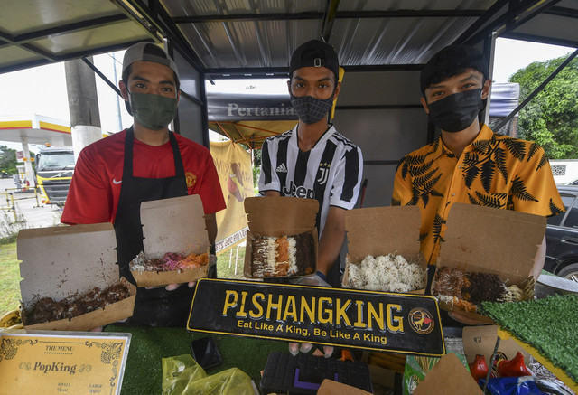 Peniaga pisang goreng keju, tiga sekawan Nik Muhammad(kiri), Muhammad Haiqal dan Shaidil (kanan), menunjukkan aneka "Pishang King Cheese" yang dijual mereka di gerai Pishang King di Jalan Pengkalan Nangka, Pengkalan Chepa, baru-baru ini. -Gambar Bernama