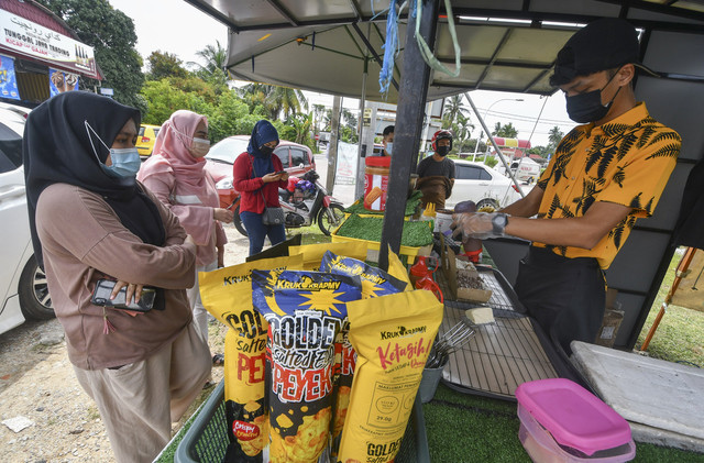 Shaidil (kanan) menyiapkan pisang goreng yang ditempah pelanggan di gerai Pishang King di Jalan Pengkalan Nangka, Pengkalan Chepa, baru-baru ini. -Gambar Bernama