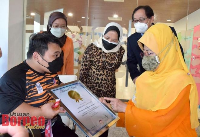 Fatimah melihat sijil pengiktirafan Malaysia Book Of Records kepunyaan Bonnie. -Gambar oleh Roystein Emmor