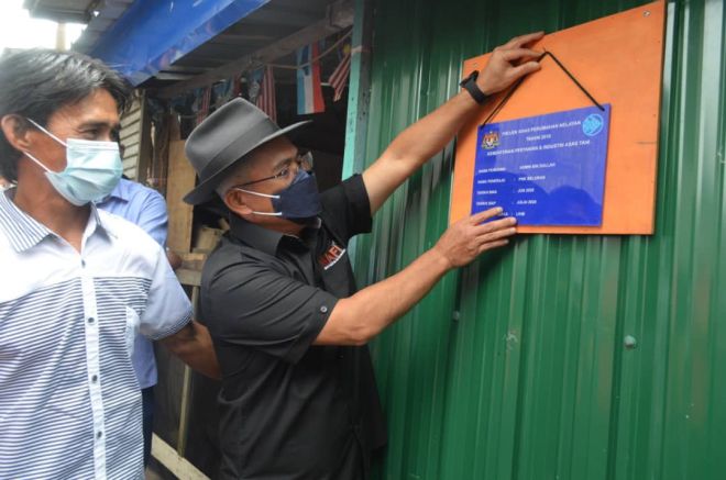 Ronald (kanan) meletakkan plak sebagai simbolik rumah baharu yang dibina di bawah PKPN untuk nelayan di Beluran.