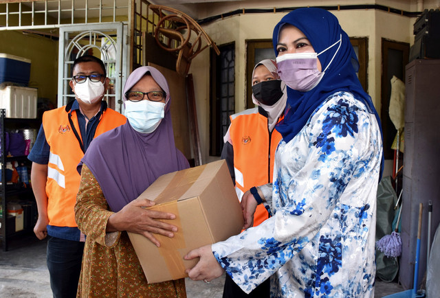 Rina (kanan) menyampaikan Bakul Prihatin kepada Narriman Husin, 56, (kiri) ketika melakukan lawatan ke rumah beliau di Jalan Cheng Lama hari ini. Pada lawatan berkenaan, Rina turut menyampaikan surat kelulusan bantuan kanak-kanak berjumlah RM300 sebulan bermula bulan depan. - Gambar Bernama 