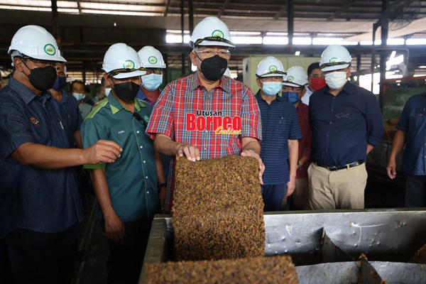  Mahdzir (tengah) menunjukkan produk getah yang diproses semasa melawat kilang berkenaan.