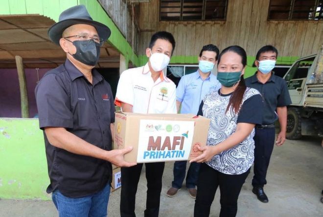 Ronald (kiri) menyampaikan bantuan MAFI Prihatin kepada penerima di Kampung Bauto Telupid.