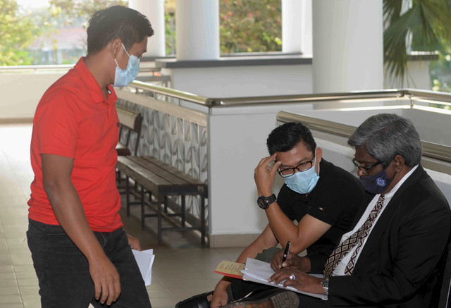 Mohd Khairul (kiri) dan Idrus (dua, kiri) berbincang dengan peguam Burhanudeen Abdul Wahid sebelum didakwa di Mahkamah Seksyen semalam berhubung menggunakan dokumen tuntutan dengan butiran palsu bagi tugasan rondaan keselamatan, pada September 2019. - Gambar Bernama 