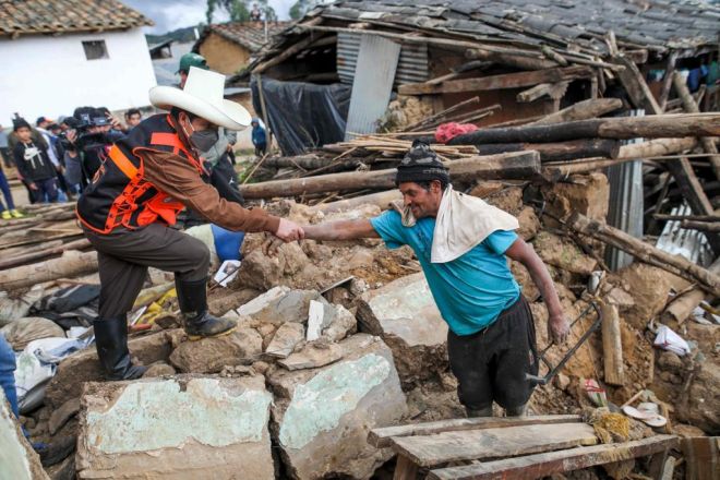 Castillo (kiri) menghulurkan tangan kepada seorang lelaki yang berdiri di tengah-tengah serpihan rumahnya yang musnah dalam kejadian gempa bumi di wilayah Amazon Peru pada Ahad lepas. - Gambar AFP