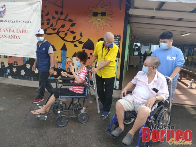  Sebastian (berbaju kuning) menyorong kerusi roda Sim, sambil berbual dengan Tan, yang dibantu oleh cucunya, selepas menunaikan kewajipan mereka mengundi di SK Jalan Bintang. 
