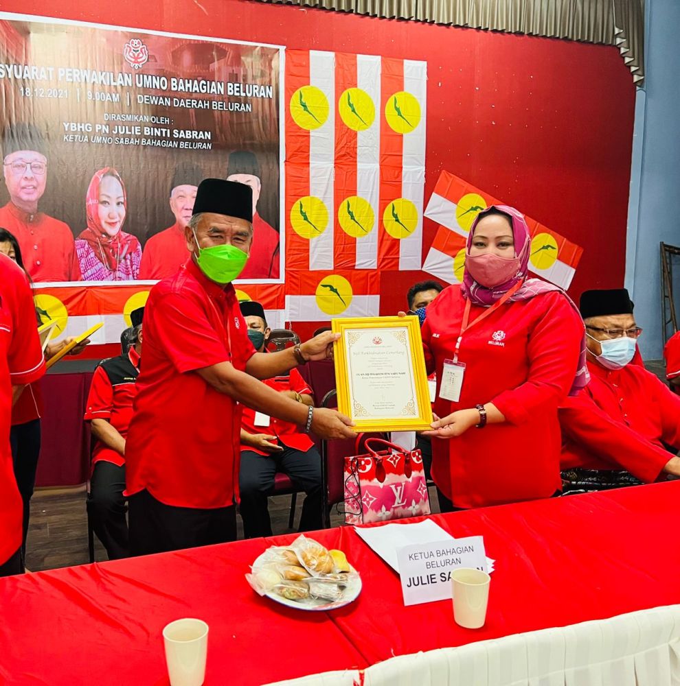 Julie menyampaikan sijil perkhidmatan cemerlang kepada salah seorang ahli semasa Mesyuarat Perwakilan Bahagian UMNO Beluran.