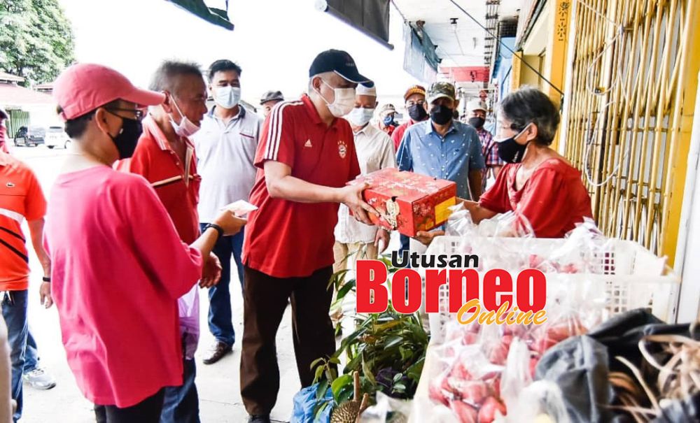  Arifin (tengah) menyampaikan limau kepada masyarakat di sekitar Pekan Membakut.