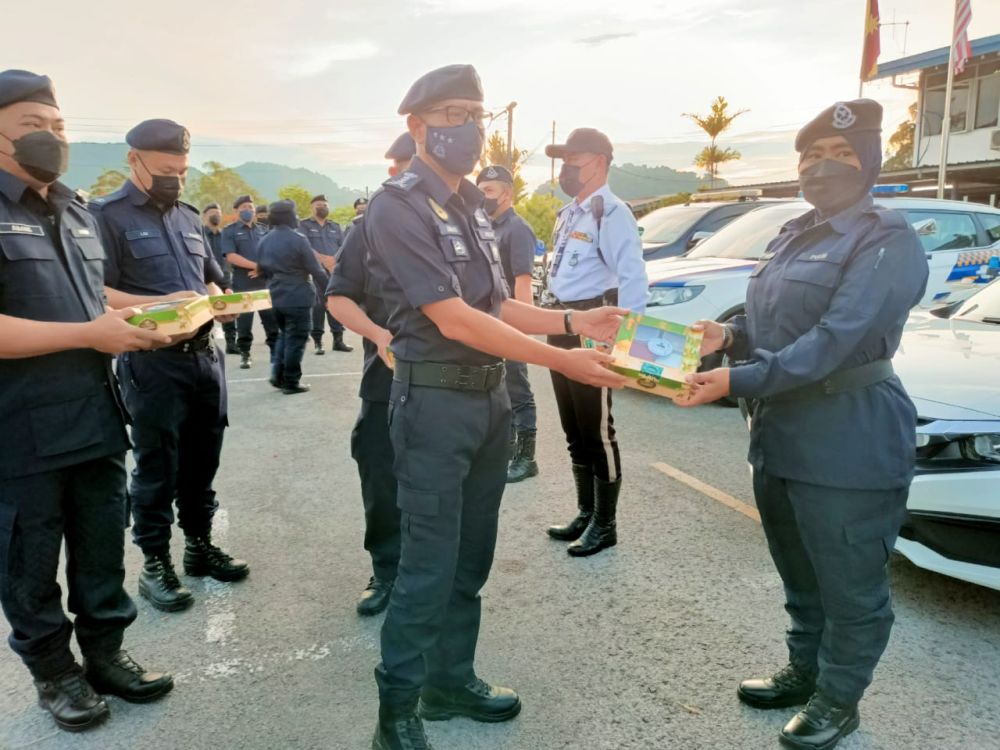 Mohd Azman (tengah) menyampaikan Sumbangan Kuih Raya kepada salah seorang wakil ketua jabatan di IPD Padawan, di sini semalam.