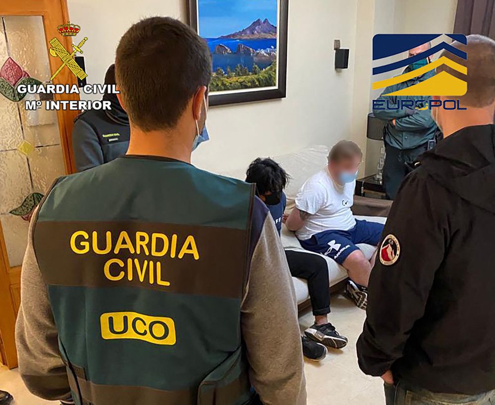 Gambar serahan Spanish Guardia Civil kelmarin menunjukkan anggota Spanish Guardia Civil berdiri di sebelah suspek yang digari semasa operasi untuk menumpaskan sindiket penggubahan wang. — Gambar AFP