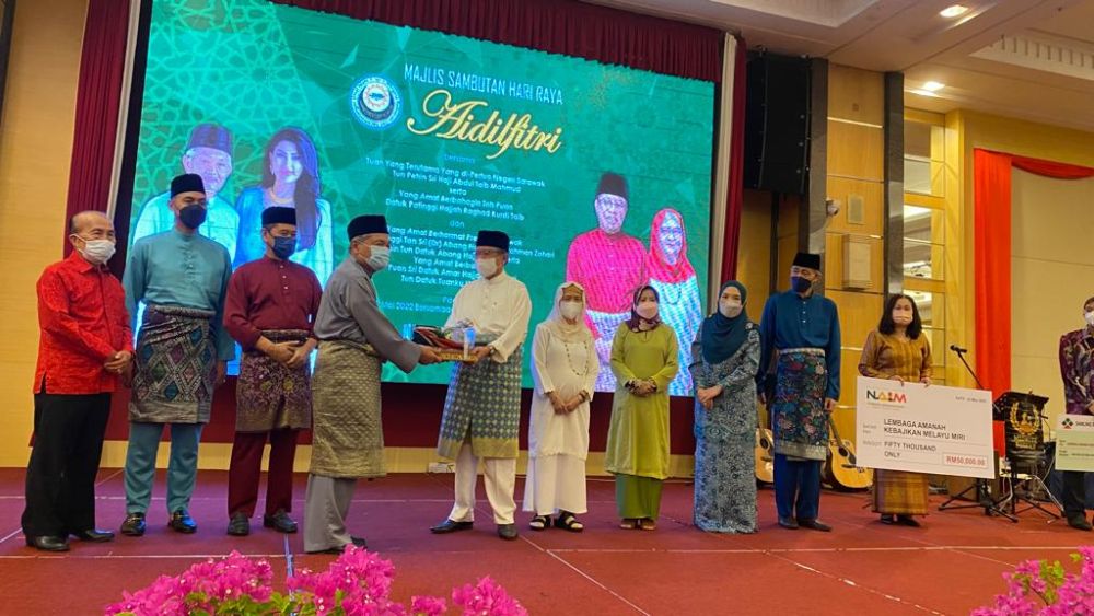 Abang Johari (kanan) nerima tepa ari Abdillah seraya diketaka bala pemesai  maya  pengerami ngintu Hari Raya Aidilfitri ti diatur Lembaga Amanah Kebajikan Melayu Miri (LAKMM) ba sebuah hotel di Miri, ensana.