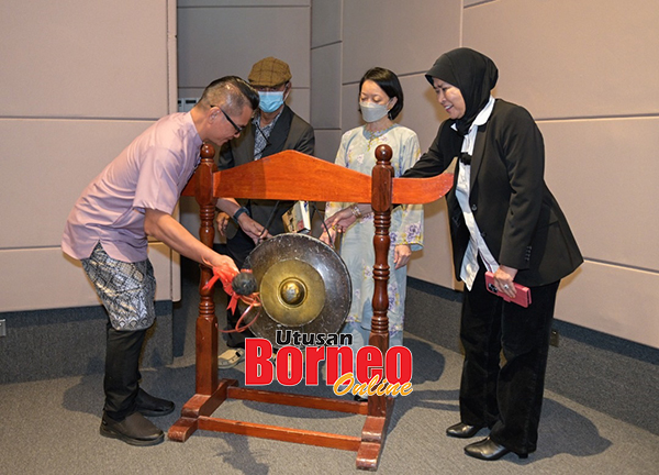  Coswald (kiri) memalu gong sebanyak tiga kali sebagai simbolik pelancaran buku sambil disaksikan Baharudin (dua kiri), Raya Erom (kanan) dan Pengarah GAH UMS, Sarlona Jasnie Gindug (dua kanan).