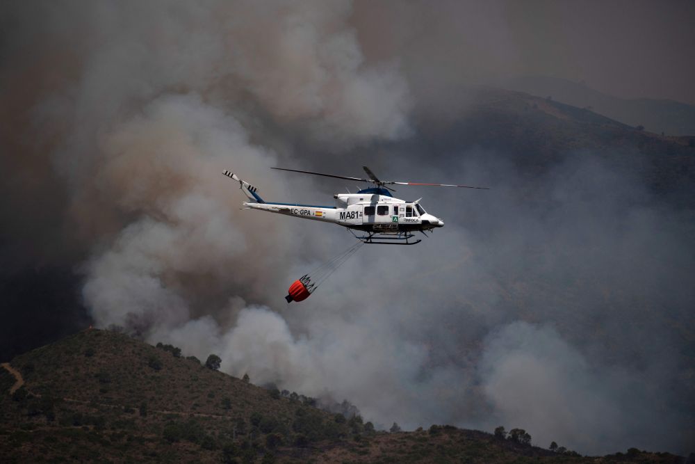 Sebuah helikopter sedang memadam kebakaran di banjaran gunung Sierra Bermeja di Malaga, kelmarin. — Gambar AFP