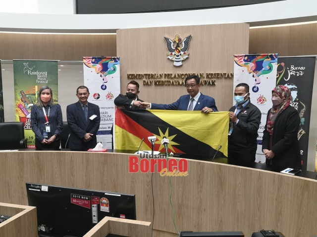 Abdul Karim (tiga kanan) menyerahkan bendera Sarawak kepada Rhemy sambil disaksikan Tazudin. – Gambar oleh Roystein Emmor