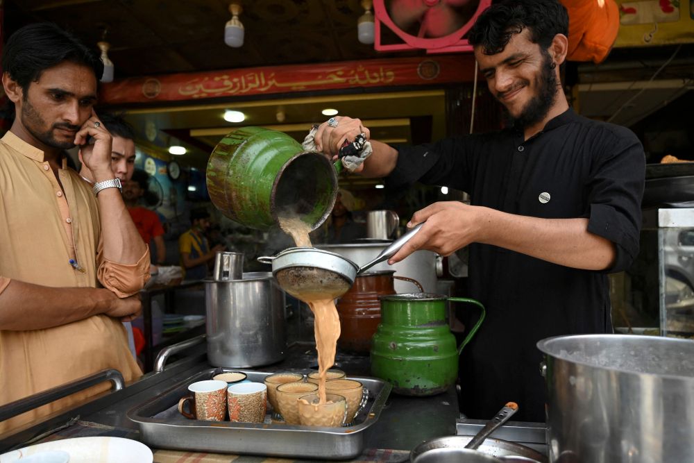 Seorang pekerja menuang teh ke dalam cawan untuk para pelanggan di sebuah restoran di Islamabad, kelmarin.