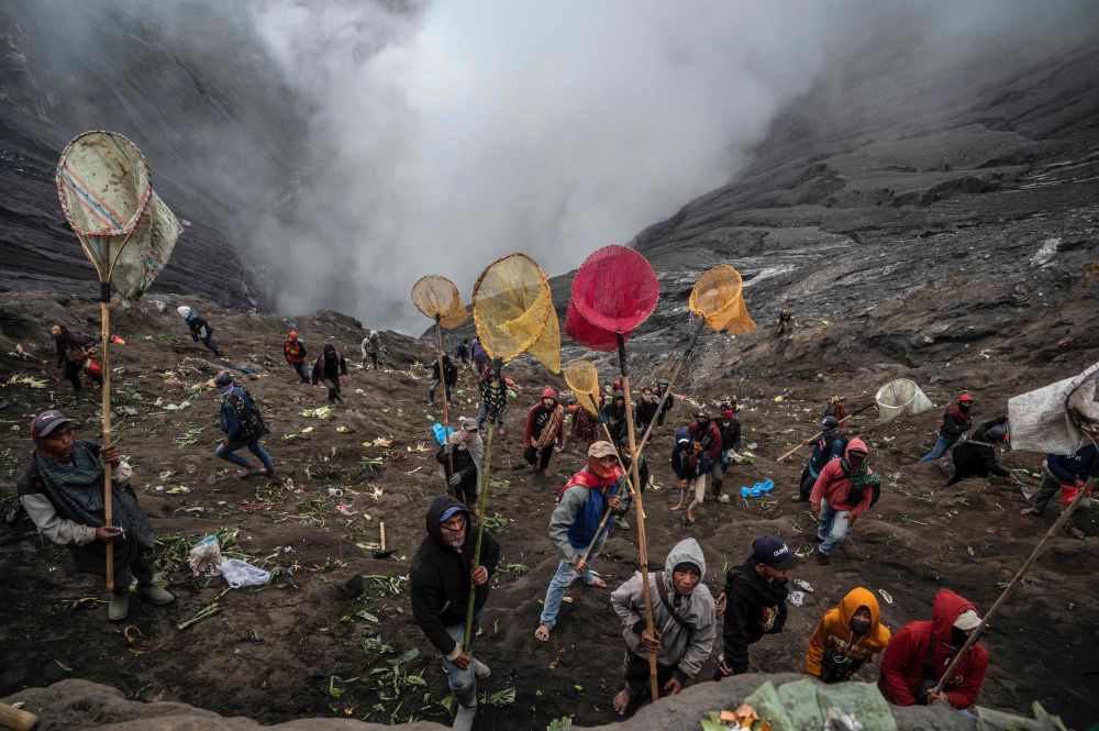 Penduduk kampung menggunakan jaring untuk menangkap persembahan yang dicampak oleh suku Tengger ketika upacara keagamaan Hindu di kawah gunung berapi Bromo yang aktif di Probolinggo, wilayah Jawa Timur kelmarin. — Gambar AFP