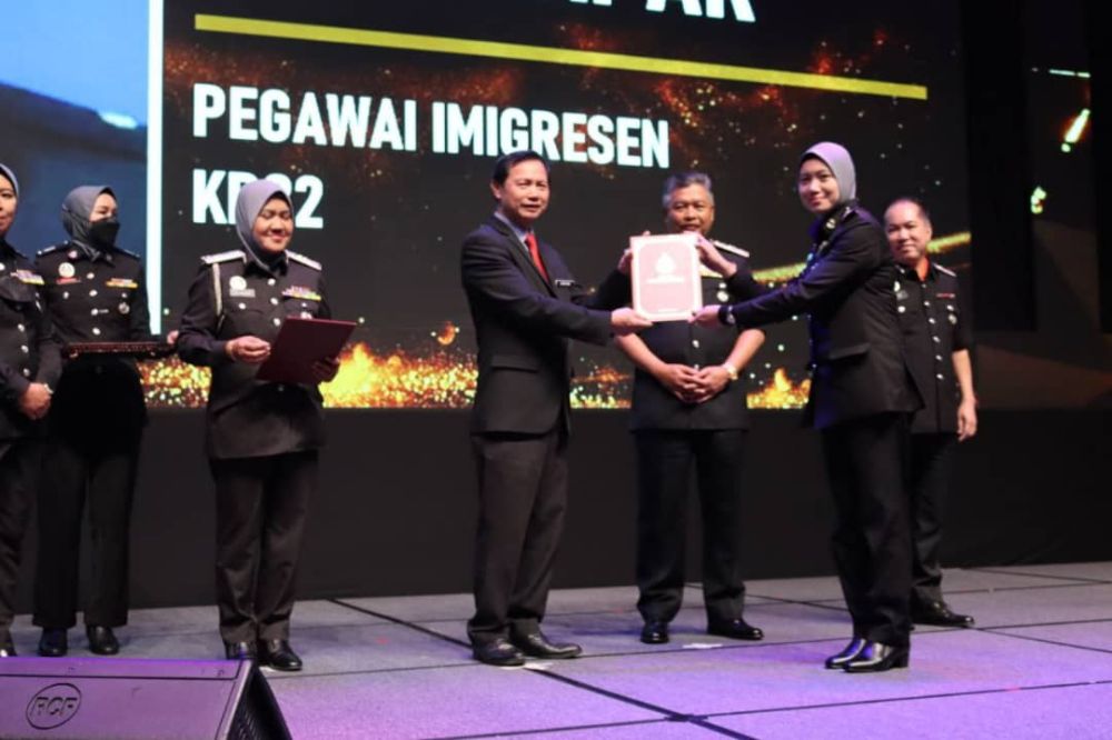  Jonathan menyampaikan sijil penghargaan kepada salah seorang penerima pada Majlis Anugerah Perkhidmatan Cemerlang 2021 JIM.