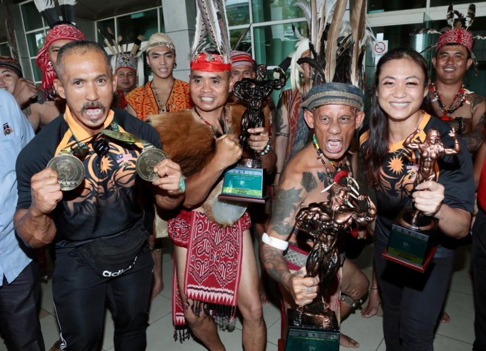 Buda (kiri) bergambar bersama Gabungan Orang Asal Sabah Sarawak yang membuat kejutan menyambut ketibaanya di Lapangan Terbang Antarabangsa, Kuching hari ini. Turut kelihatan, Philomena (kanan). - Gambar Muhamad Rais Sanusi