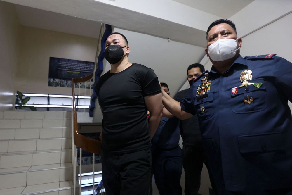 Yumol (kiri) diiringi polis di Kem Karingal berikutan penangkapan beliau selepas menembak mati tiga orang di Ateneo de Manila University, Manila, kelmarin. — Gambar AFP