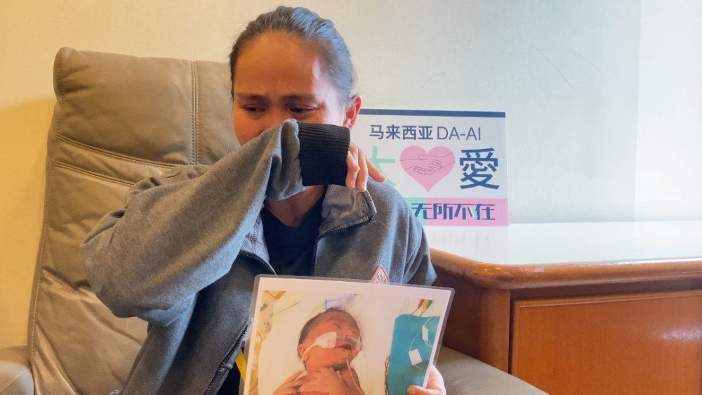 Entia memegang gambar anaknya Federick yang telah didiagnosis dengan TGA, sejenis kecacatan jantung kongenital. – Foto ihsan Da-Ai Malaysia Social Crowdfunding