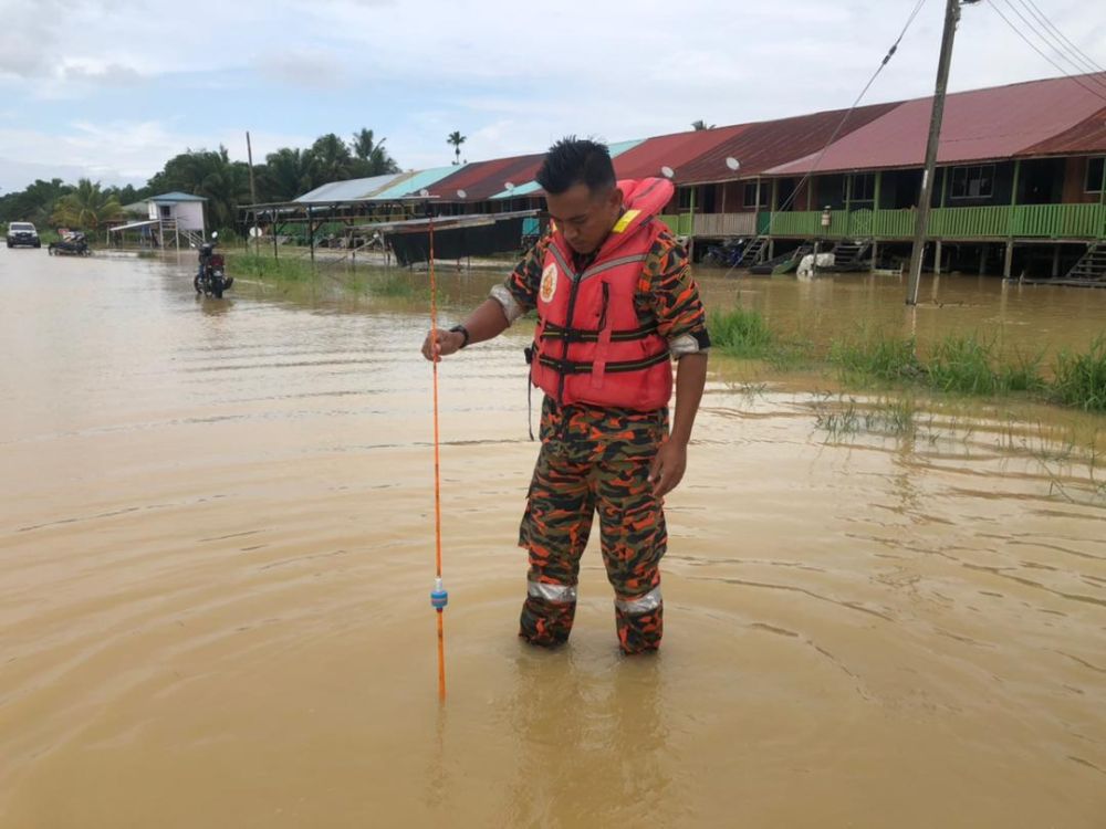 Anggota bomba melakukan pemantauan paras air banjir yang melanda kawasan Rumah Ayai Sawing. 