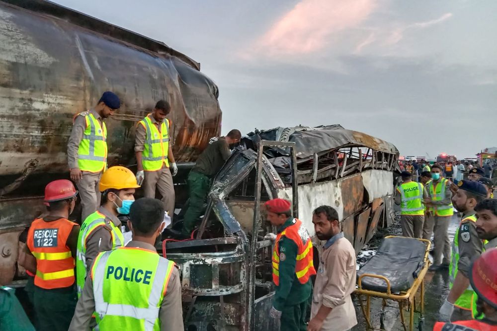 Anggota penyelamat menggeledah rangka bas yang rentung selepas ia bertembung dengan sebuah lori tangki minyak di daerah Multan, Pakistan kelmarin. — Gambar AFP