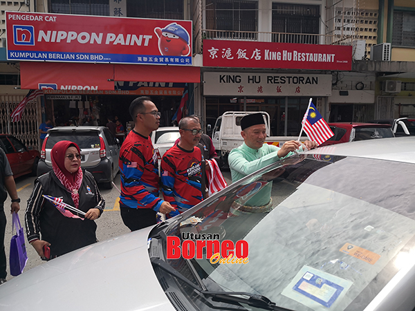  Reduan melekatkan bendera Jalur Gemilang pada kenderaan awam di Tanjung Aru.