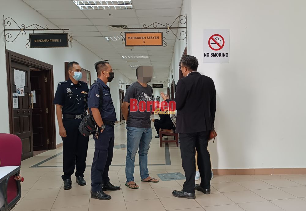 Tertuduh (dua kanan) berbual dengan seorang lagi peguam di Kompleks Mahkamah Kuching hari ini.