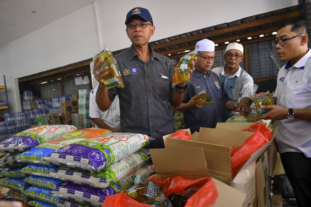  Rosol Wahid (kiri) membuat tinjauan bekalan minyak masak paket pada Program Jualan Murah Keluarga Malaysia di Kampung Beladau Kepong, Kuala Terengganu. - Gambar Bernama
