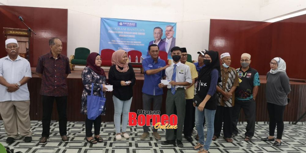  Seorang pelajar menerima bantuan daripada Jeffery (lima kiri) ketika dimajlis berkenaan.