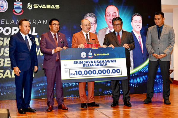  Hajiji (tengah) menyerahkan replika cek RM10 juta kepada Ellron (dua kanan) sebagai simbolik pelancaran Portal SYABAS. 