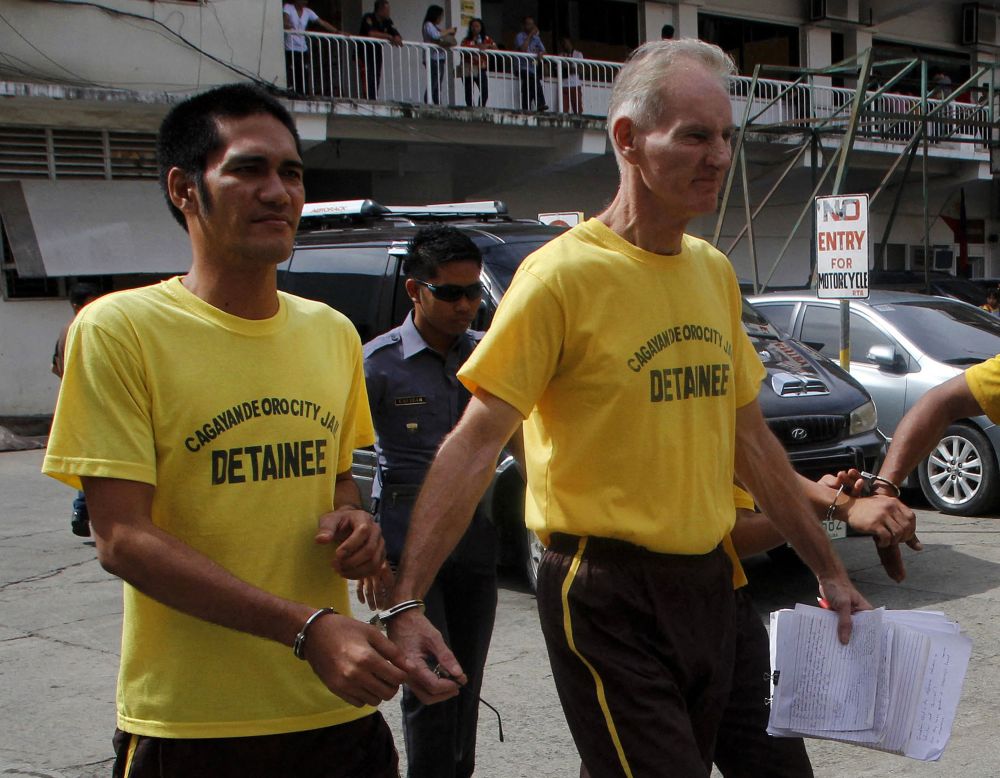  Gambar fail pada 16 Jun, 2015 menunjukkan Scully (kanan) digari bersama seorang banduan lain ketika meninggalkan mahkamah di bandar Cagayan de Oro, Mindanao. — Gambar AFP 