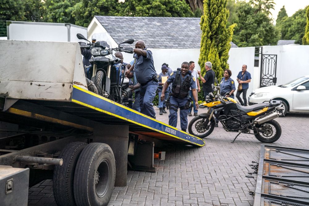 Pegawai Perkhidmatan Polis Afrika Selatan (SAPS) memunggah motosikal yang dirampas ke atas sebuah trak di luar rumah di Bryanston, Johannesburg kelmarin ekoran penangkapan seorang ketua geng Israel yang berada dalam senarai merah Interpol sejak 2015. — Gambar AFP