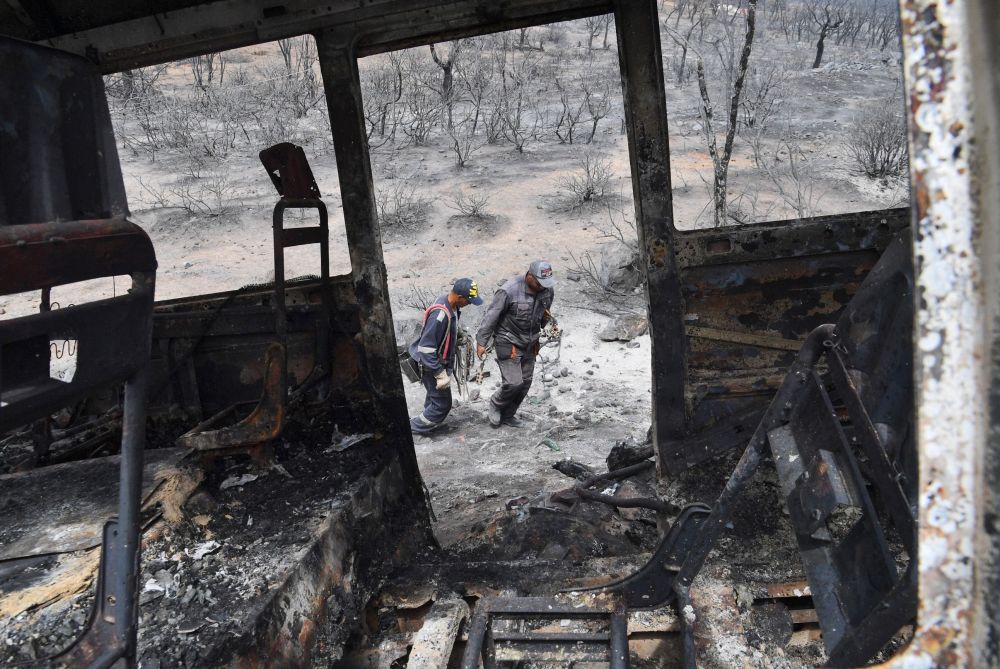 Gambar fail 18 Ogos menunjukkan anggota bomba melintasi sebuah rangka bas di mana 12 orang dilaporkan maut ekoran kebakaran hutan di bandar El-Kala, Algeria. — Gambar AFP
