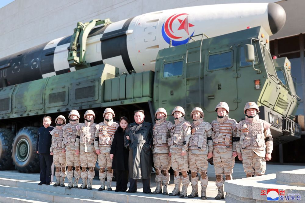 Gambar tidak bertarikh serahan KCNA semalam menunjukkan Kim bersama anak perempuannya bergambar bersama anggota tentera yang terlibat dalam ujian pelancaran ICBM di lokasi tidak didedahkan di Korea Utara. - Gambar AFP