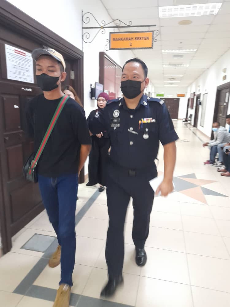 Remaja tersebut (kiri) diiring polis selesai keluar dari kamar Mahkamah Sesyen di Kuching hari ini.