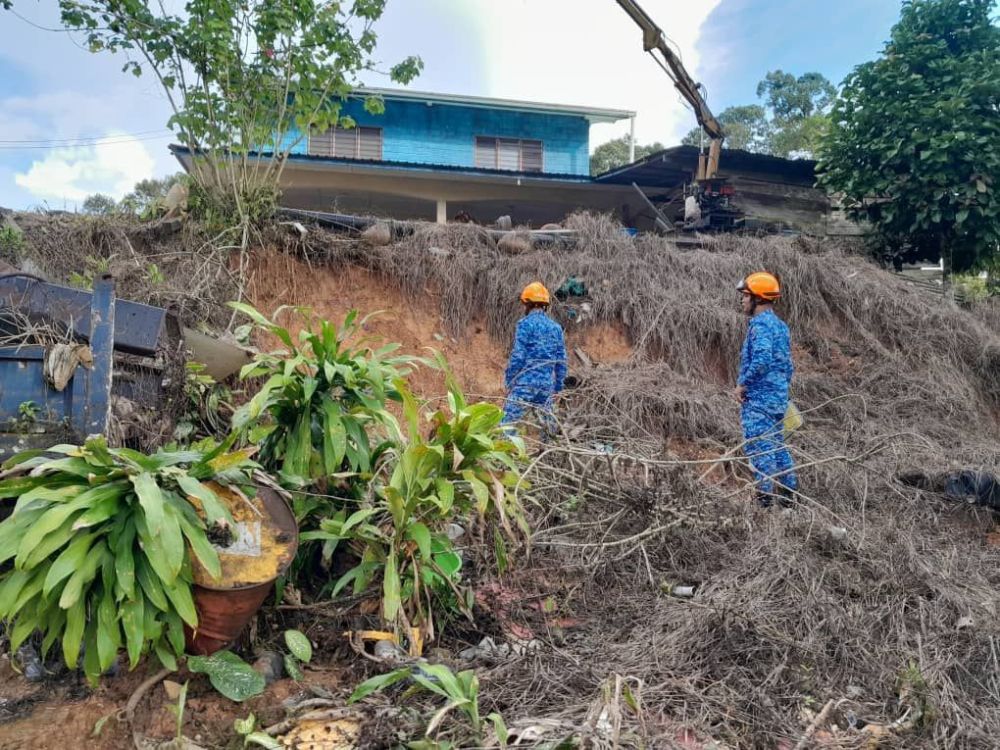 Anggota APM melakukan pemeriksaan tanah susur yang berlaku di hadapan sebuah rumah di Sungai Jakar, Sarikei pada Khamis.