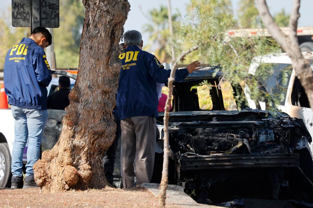 Pegawai penyiasat polis memeriksa kenderaan yang dibakar oleh perompak yang melarikan diri selepas gagal merompak AS$32.5 juta di Lapangan Terbang Antarabangsa Arturo Merino Benitez di Santiago, Chile kelmarin. — Gambar AFP 