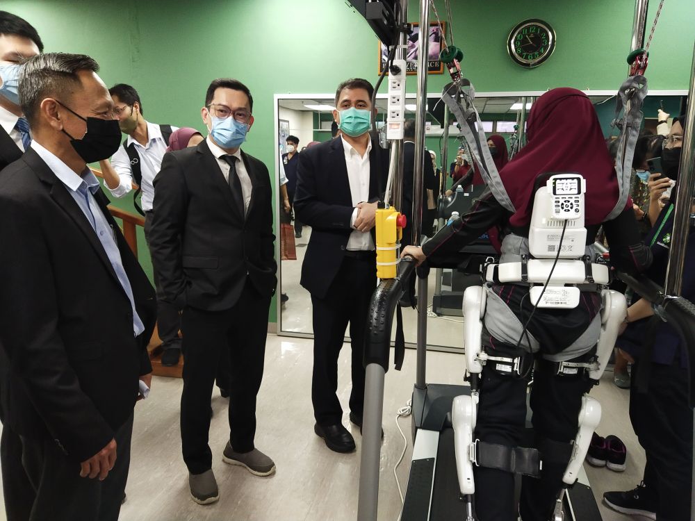 Hafez (tiga kiri) dan Dr Tan (dua kiri) melihat salah seorang pesakit yang sedang menjalani rawatan terapi robotik di NMSC. Turut kelihatan, Pengarah PERKESO Sarawak Tan Phang Chia (kiri). 