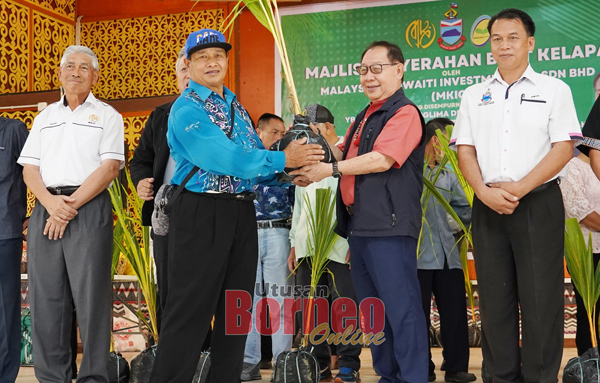  Jeffrey (dua kanan) menyampaikan sumbangan benih kelapa kepada salah seorang petani.