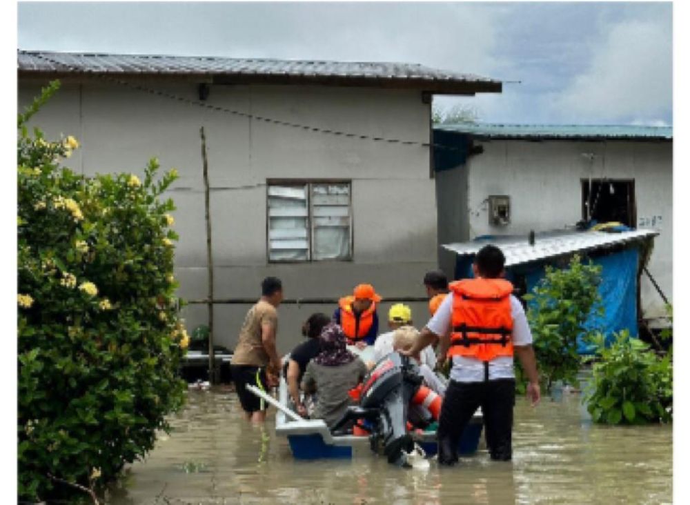 Pasukan keselamatan membantu membawa mangsa banjir untuk dipindahkan ke PPS berdekatan yang disediakan.