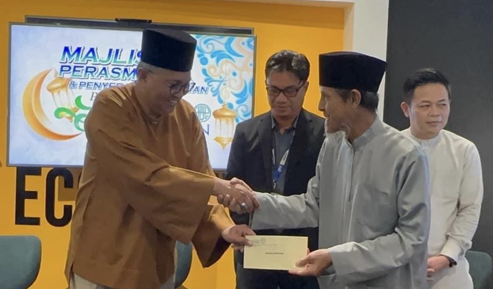 Abang Mohd Shibli (kiri) menyampaikan sumbangan kepada salah seorang penerima pada Majlis Pelancaran Program Kasih Ramadan dan Penyerahan Bantuan TBS di Kuching, pada Jumaat.