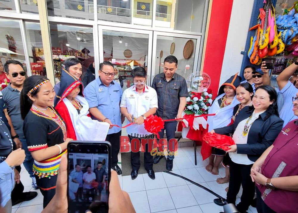  Ewon (tengah) memotong reben sebagai simbolik perasmian Pusat Produk IKS Mart Koperasi Usahaniaga Kota Marudu Berhad.