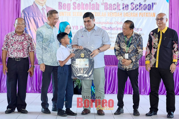  Shahhelmey (tiga kanan) menyampaikan sumbangan beg sekolah kepada salah seorang murid sekolah.