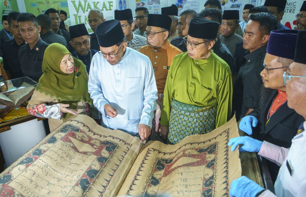 Anwar diberi penerangan mengenai al-Quran tulisan tangan semasa melawat pameran selepas merasmikan Seminar Antarabangsa Imam As-Syafi'i di BCCK, hari ini. - Gambar Muhammad Rais Sanusi