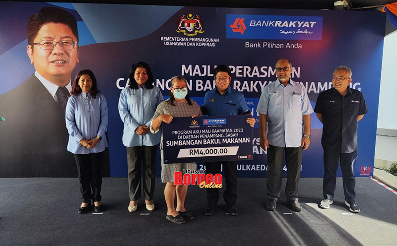  Ewon (tengah) menyempurnakan gimik penyerahan bantuan CSR kepada seorang penerima.